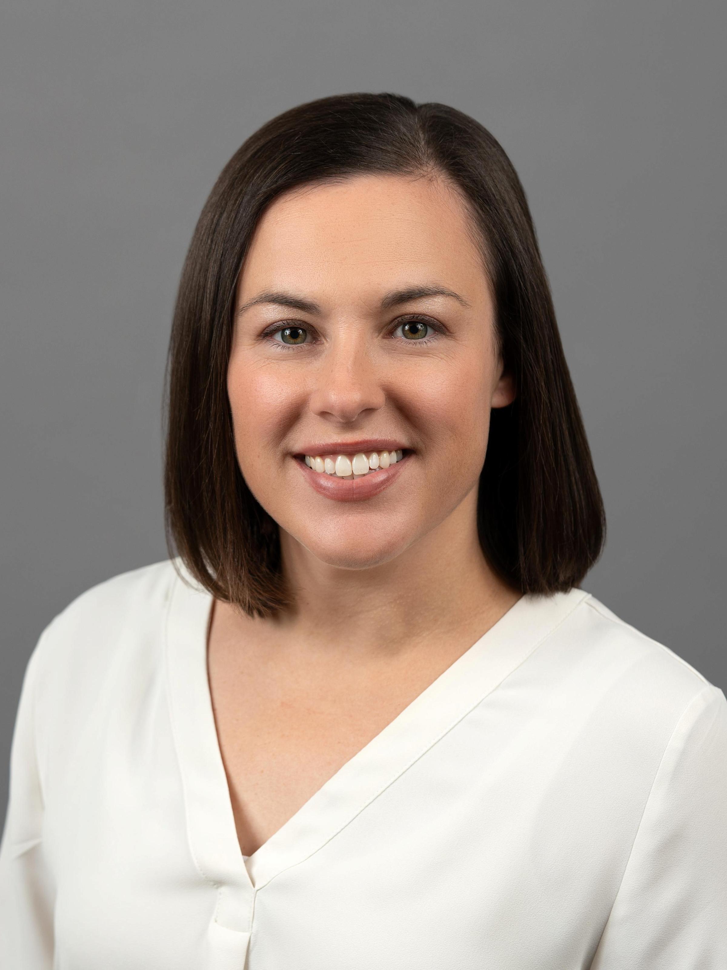 Nicola White smiling headshot, shoulder length dark brown hair